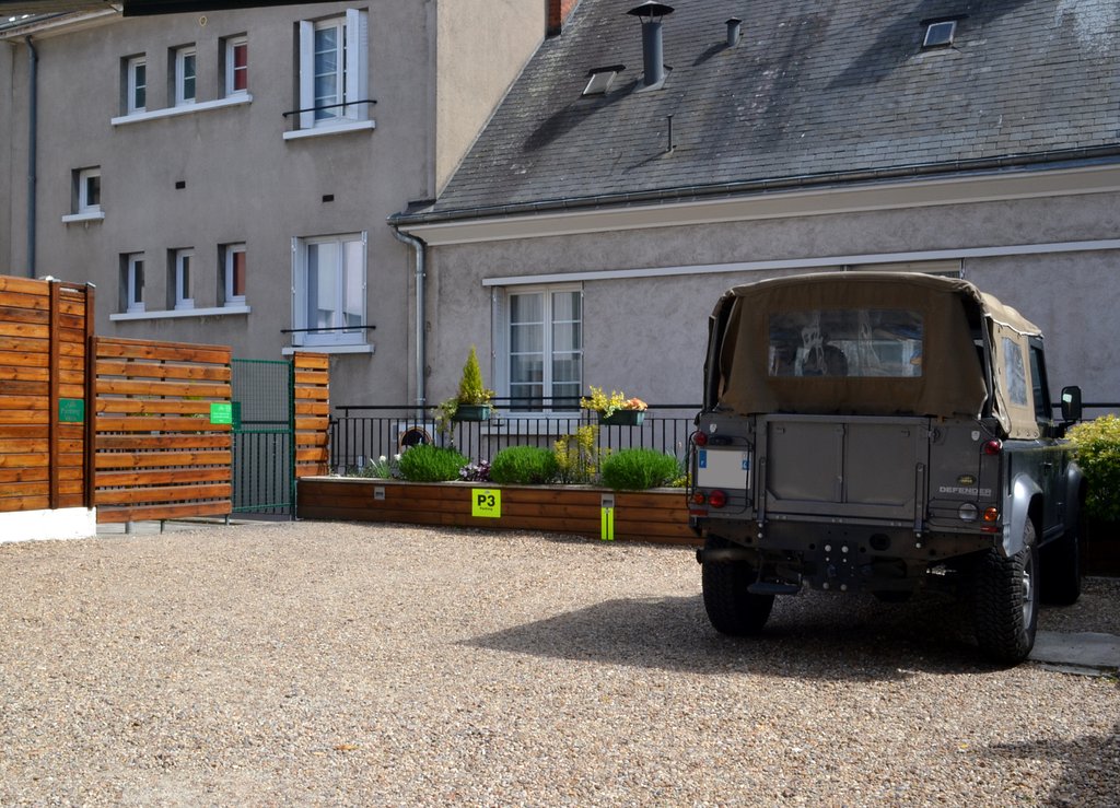 Parking privé sécurisé de l’hôtel : cour gravillonnée, clôture en bois et portail