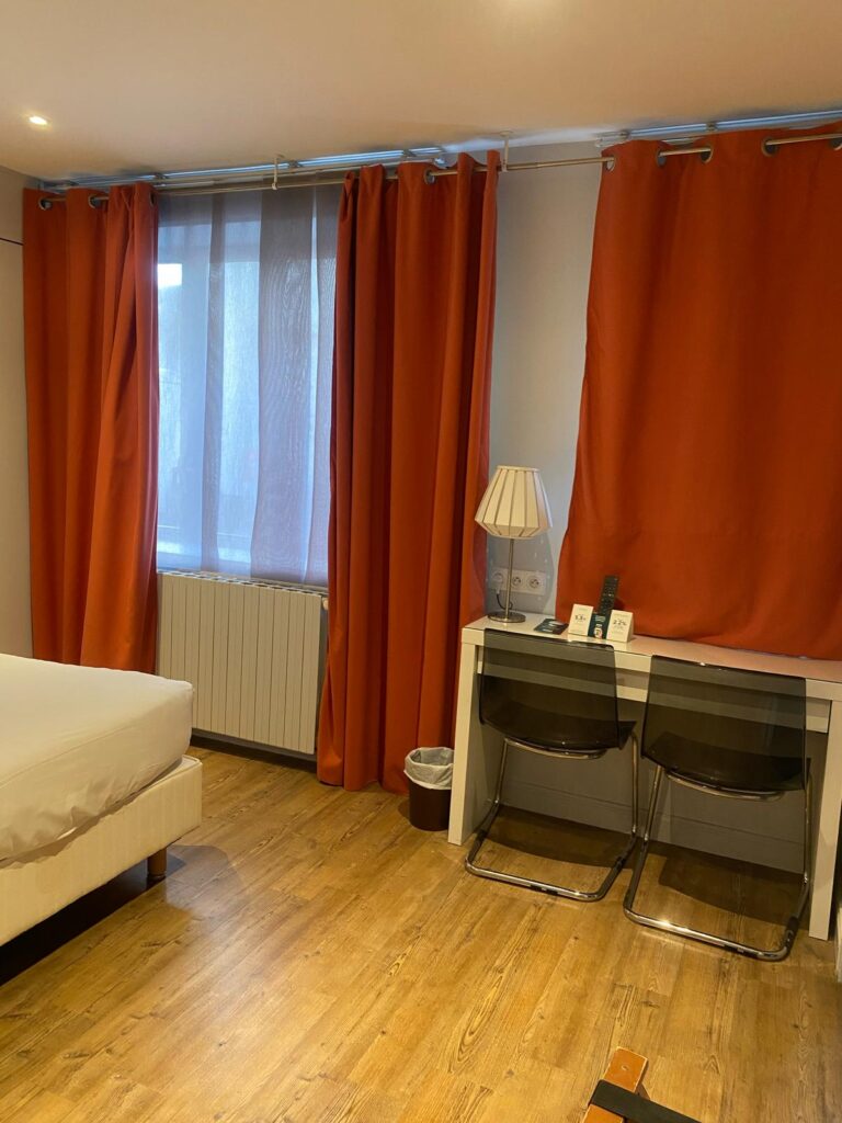 Chambre PMR : fenêtre à rideaux orange et coin bureau