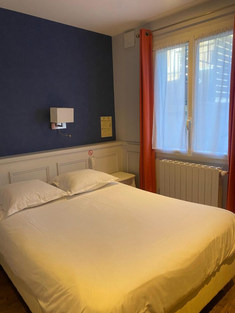 Chambre PMR : lit et fenêtre à rideaux orange
