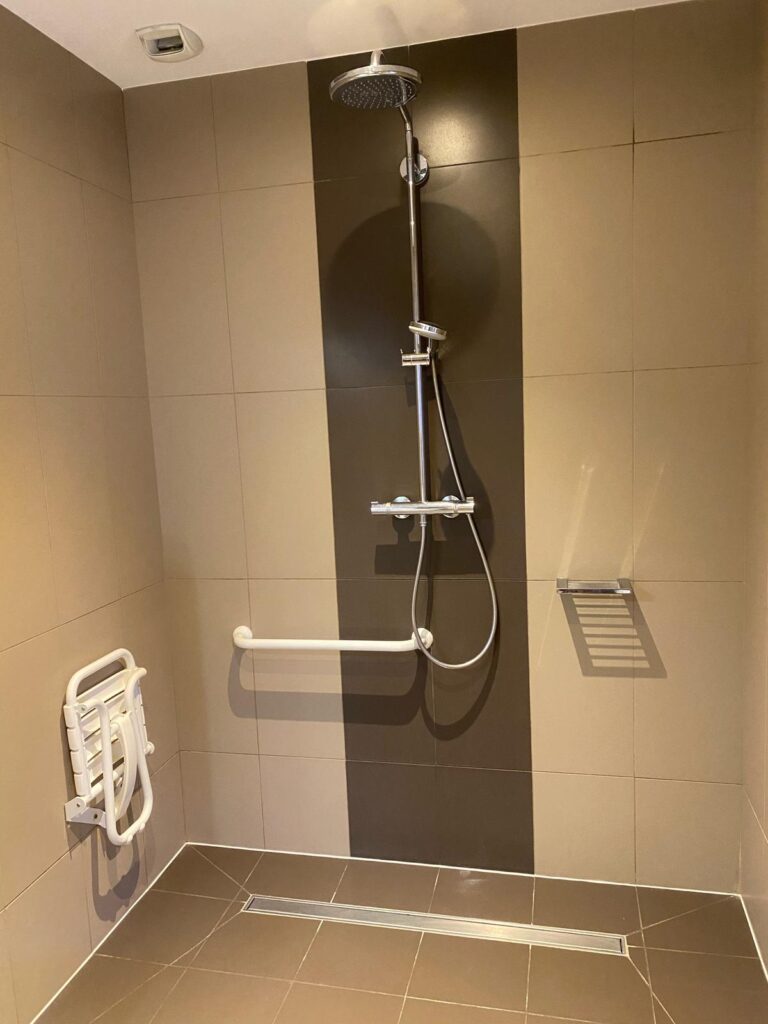 Salle de bains d’une chambre PMR : douche carrelée