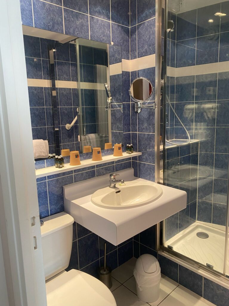 Salle de bains carrelée de bleu : lavabo, miroir et douche