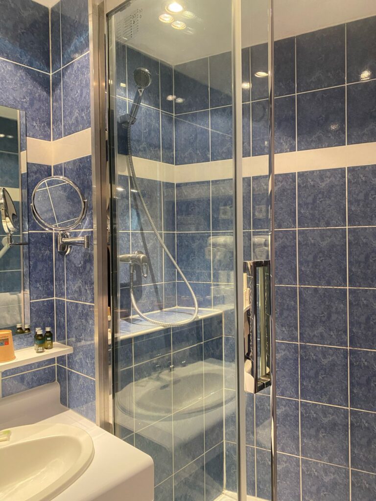 Salle de bains carrelée de bleu : douche vitrée et lavabo