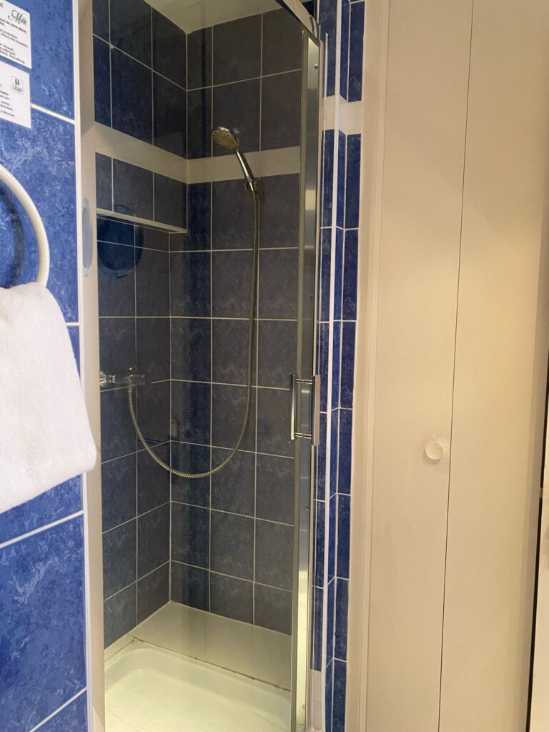 Salle de bains carrelée de bleu avec douche